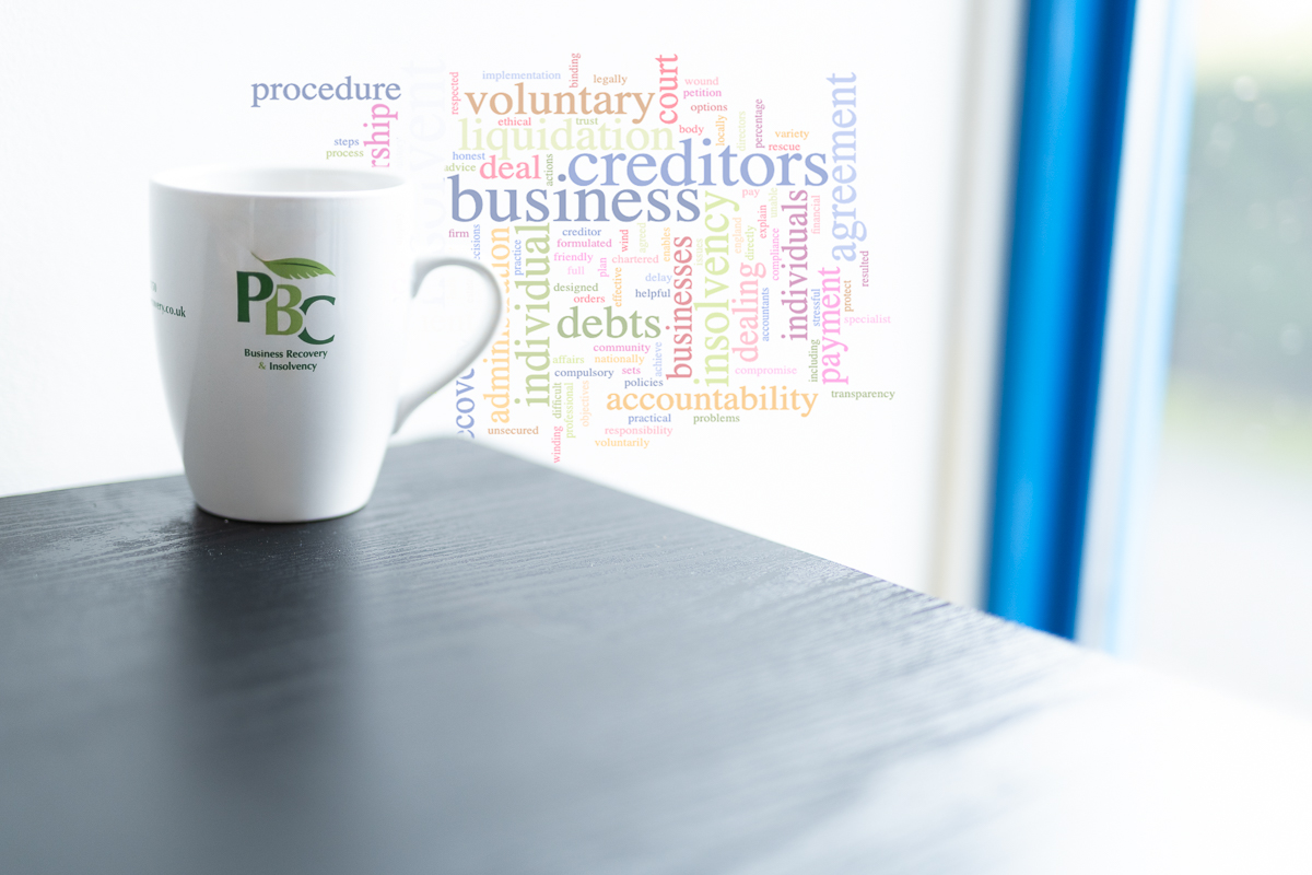 PBC mug with insolvency related words behind